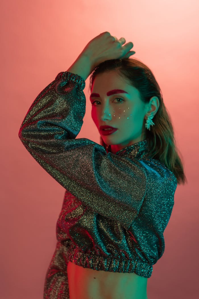 Vibrant studio portrait of a woman with glitter makeup posing gracefully.